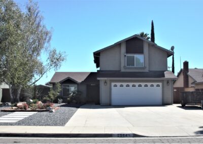 A two-story suburban house with a double garage and xeriscaped front yard.