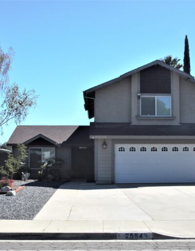 A two-story suburban house with a double garage and xeriscaped front yard.